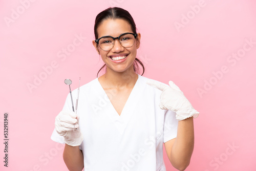 Dentist Colombian woman isolated on pink background giving a thumbs up gesture