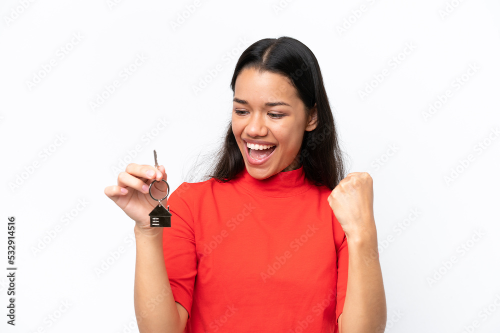 Young Colombian woman holding home keys isolated on white background celebrating a victory Young Colombian woman holding home keys isolated on white background celebrating a victory