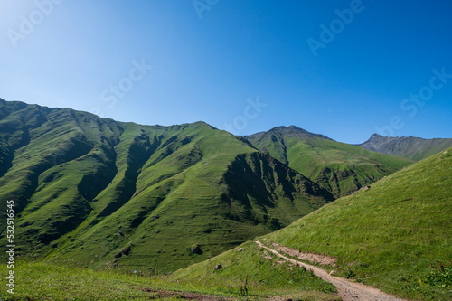 Scenic road and surrounding mountain landscape with forests around view Juta village near Caucasus mountain in Kazbegi, Georgia - Panoramic Landscape of Beautiful Georgian Mountains.