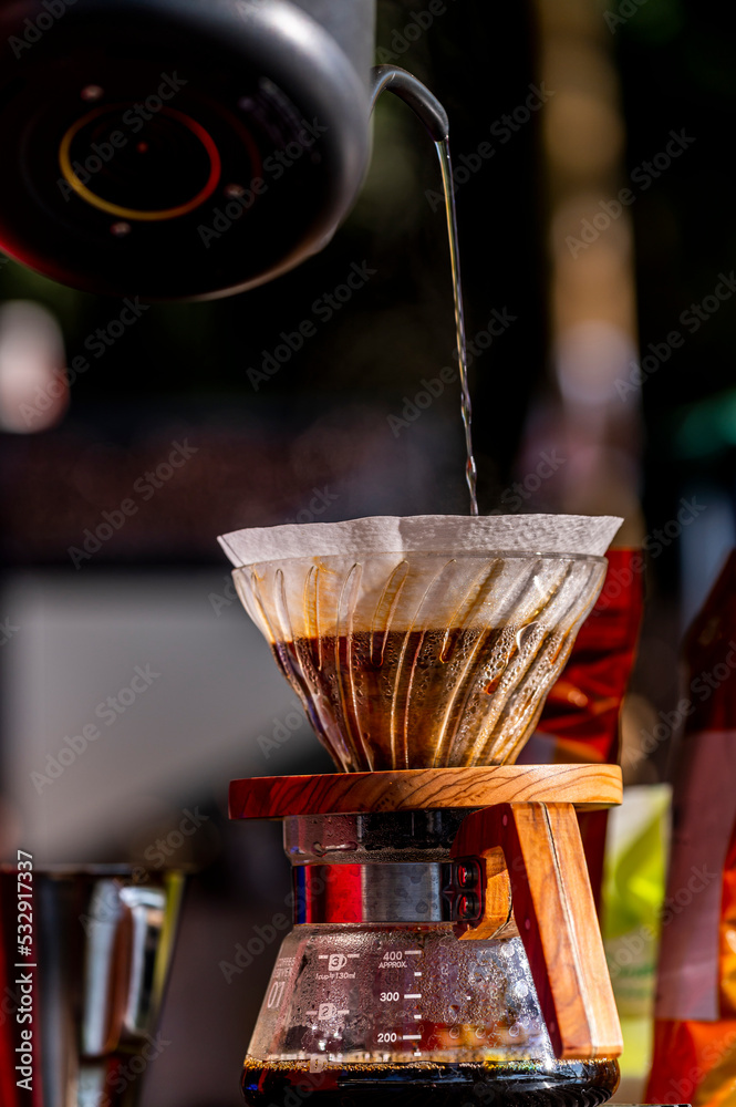Professional barista pour hot water over the coffee powder in a filter on chemex pour over