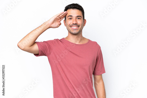 Young handsome man over isolated white background saluting with hand with happy expression