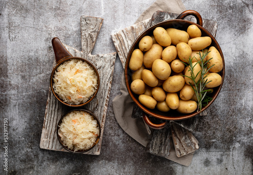 Raw small potatoes in a cast iron skillet on a beton background.
