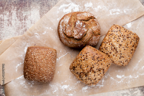 Gold rustic crusty loaves of bread and buns on wooden background. Still life captured from above top view, flat lay.