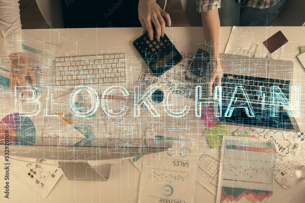 Double exposure of man and woman working together and crypto finance theme hologram. Blockchain business concept. Computer background.