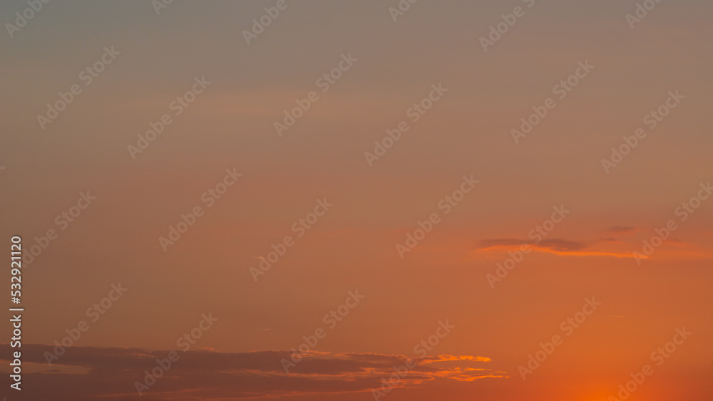 Soft deep orange sky, illuminated clouds at bloody sunset as a background.