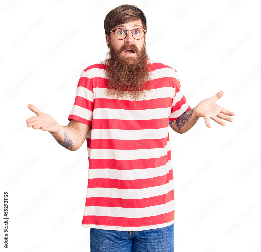 Handsome young red head man with long beard wearing casual clothes clueless and confused expression with arms and hands raised. doubt concept. Handsome young red head man with long beard wearing casual clothes clueless and confused expression with arms and hands raised. doubt concept.