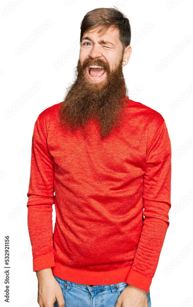 Redhead man with long beard wearing casual clothes winking looking at the camera with sexy expression, cheerful and happy face. Redhead man with long beard wearing casual clothes winking looking at the camera with sexy expression, cheerful and happy face.