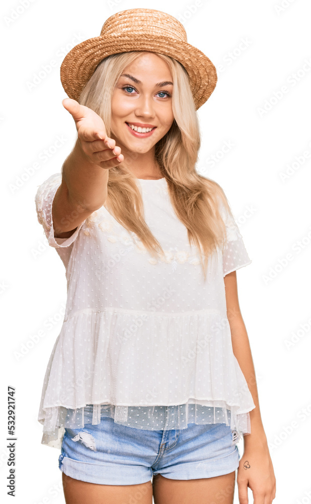 Young blonde girl wearing summer hat smiling friendly offering handshake as greeting and welcoming. successful business. Young blonde girl wearing summer hat smiling friendly offering handshake as greeting and welcoming. successful business.