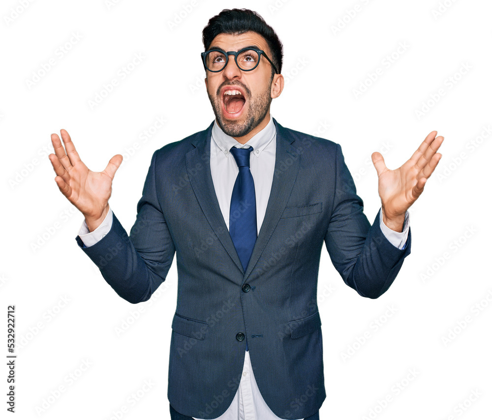Hispanic man with beard wearing business suit and tie crazy and mad shouting and yelling with aggressive expression and arms raised. frustration concept. Hispanic man with beard wearing business suit and tie crazy and mad shouting and yelling with aggressive expression and arms raised. frustration concept.