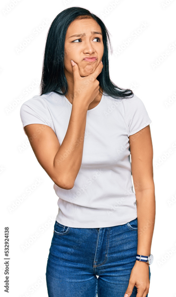 Beautiful hispanic woman wearing casual white tshirt thinking worried about a question, concerned and nervous with hand on chin Beautiful hispanic woman wearing casual white tshirt thinking worried about a question, concerned and nervous with hand on chin
