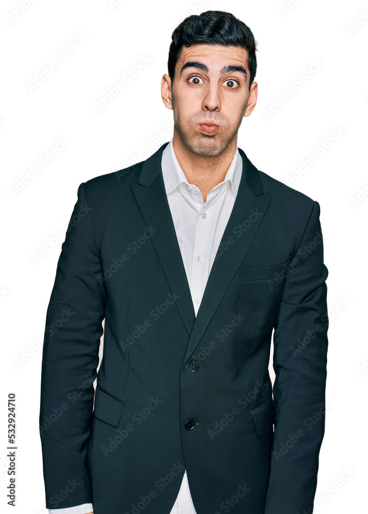 Handsome hispanic man wearing business clothes puffing cheeks with funny face. mouth inflated with air, crazy expression. Handsome hispanic man wearing business clothes puffing cheeks with funny face. mouth inflated with air, crazy expression.