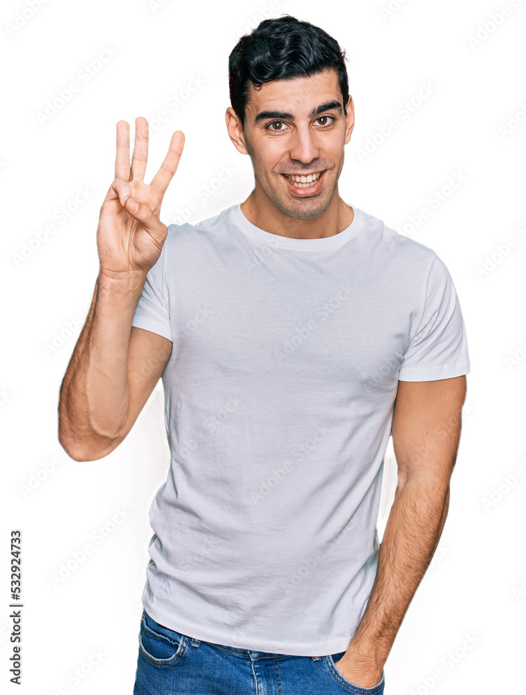 Handsome hispanic man wearing casual white t shirt showing and pointing up with fingers number three while smiling confident and happy. Handsome hispanic man wearing casual white t shirt showing and pointing up with fingers number three while smiling confident and happy.