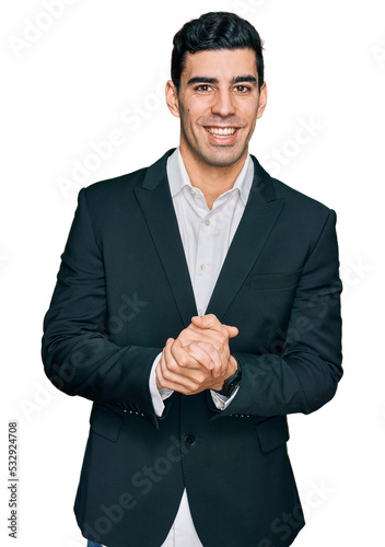 Handsome hispanic man wearing business clothes with hands together and crossed fingers smiling relaxed and cheerful. success and optimistic