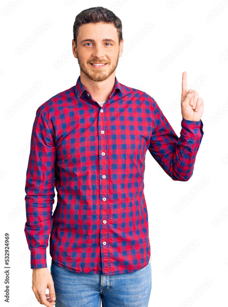 Handsome young man with bear wearing casual shirt pointing finger up with successful idea. exited and happy. number one. Handsome young man with bear wearing casual shirt pointing finger up with successful idea. exited and happy. number one.