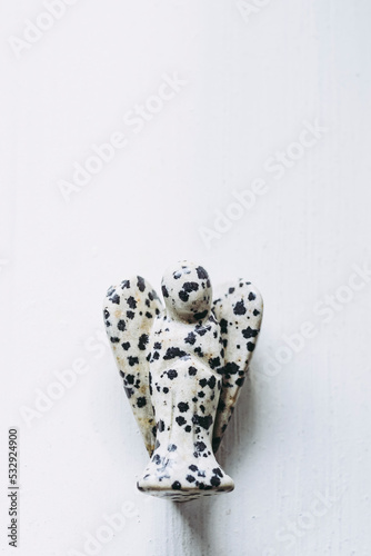 Ange en pierre semi-précieuse jaspe dalmatien sur fond blanc - Minéral naturel