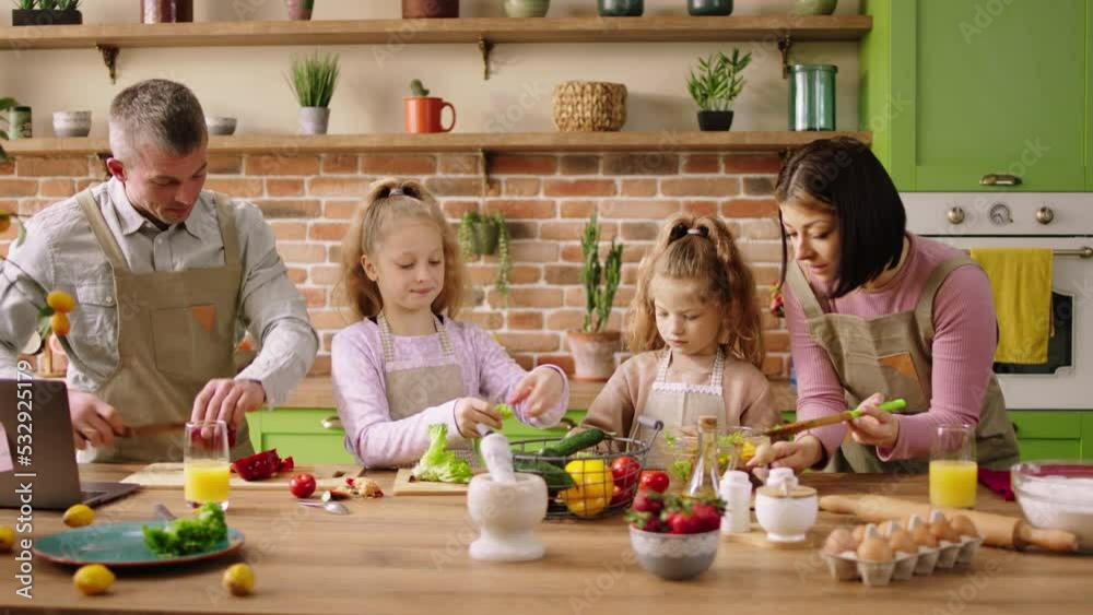 In a modern kitchen at home Caucasian parents and their two kids happy preparing the dinner together cut some vegetables for a healthy salad In a modern kitchen at home Caucasian parents and their two kids happy preparing the dinner together cut some vegetables for a healthy salad
