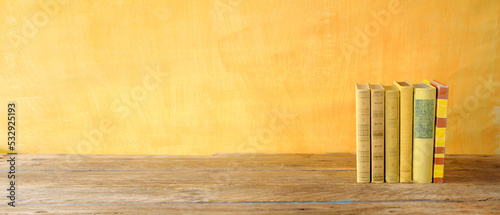 Row of yellow books on yellow background, inspiration,reading, education, literature  concept,  panoramic, large free copy space photo