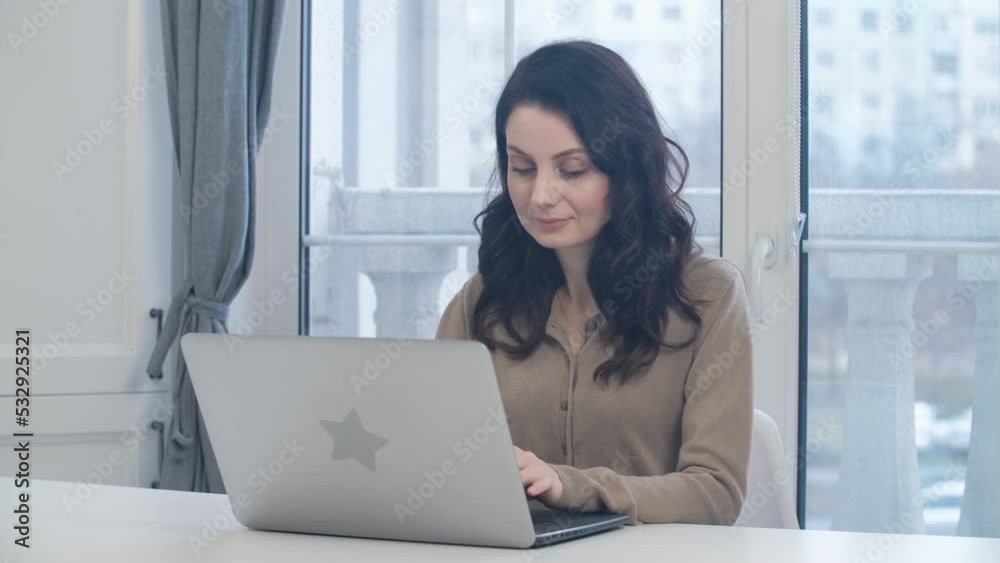 White woman working on laptop at home. Freelancer female person doing distant work on notebook computer White woman working on laptop at home. Freelancer female person doing distant work on notebook computer