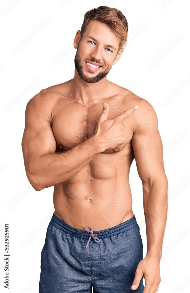 Fototapeta premium Young caucasian man standing shirtless cheerful with a smile of face pointing with hand and finger up to the side with happy and natural expression on face