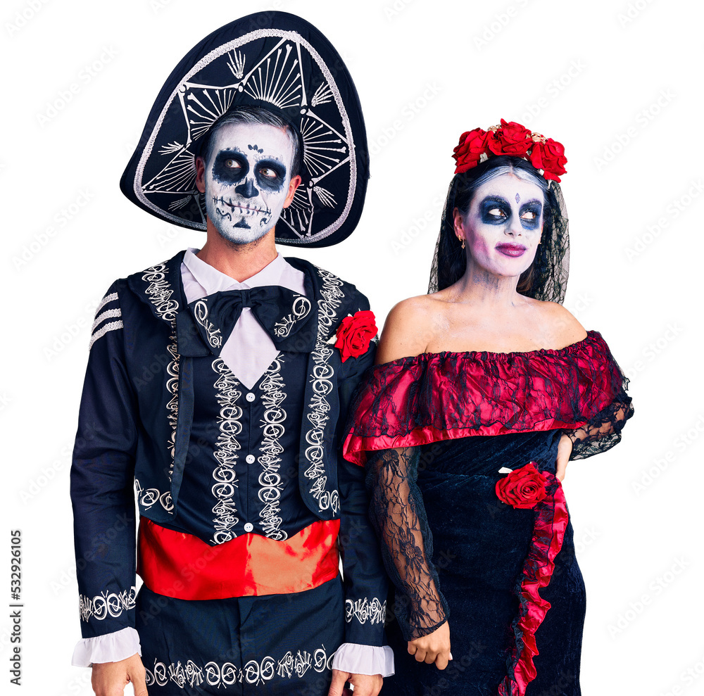 Young couple wearing mexican day of the dead costume over background smiling looking to the side and staring away thinking.