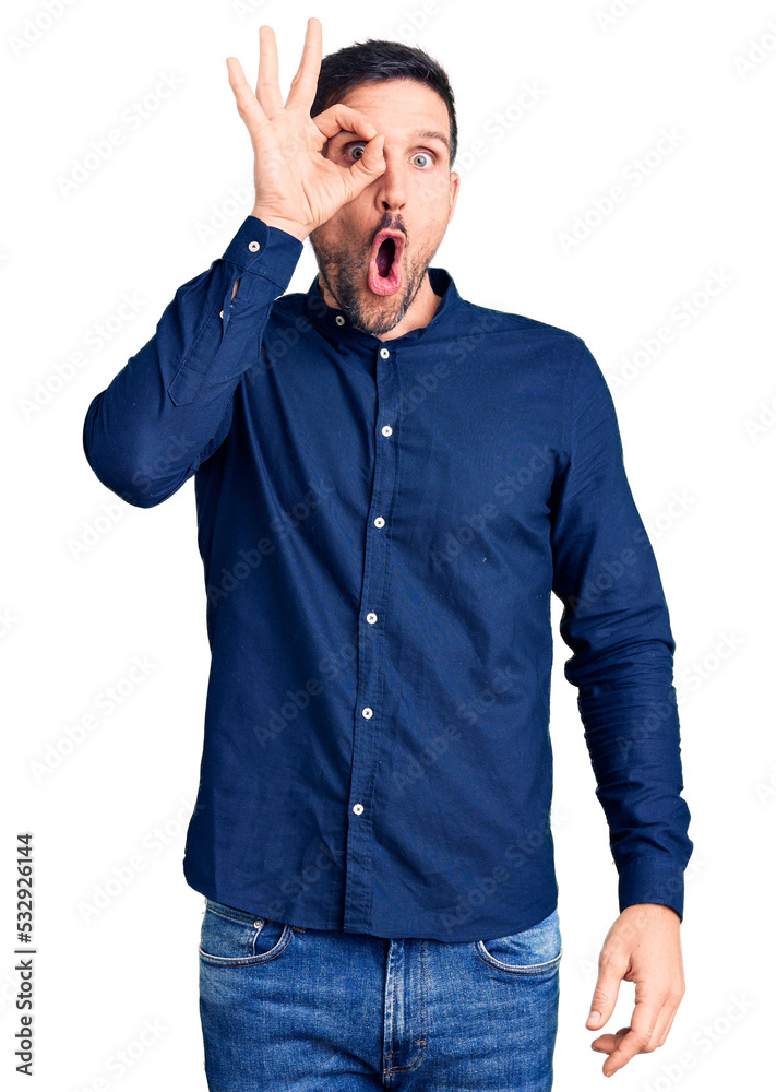 Young handsome man wearing casual shirt doing ok gesture shocked with surprised face, eye looking through fingers. unbelieving expression. Young handsome man wearing casual shirt doing ok gesture shocked with surprised face, eye looking through fingers. unbelieving expression.