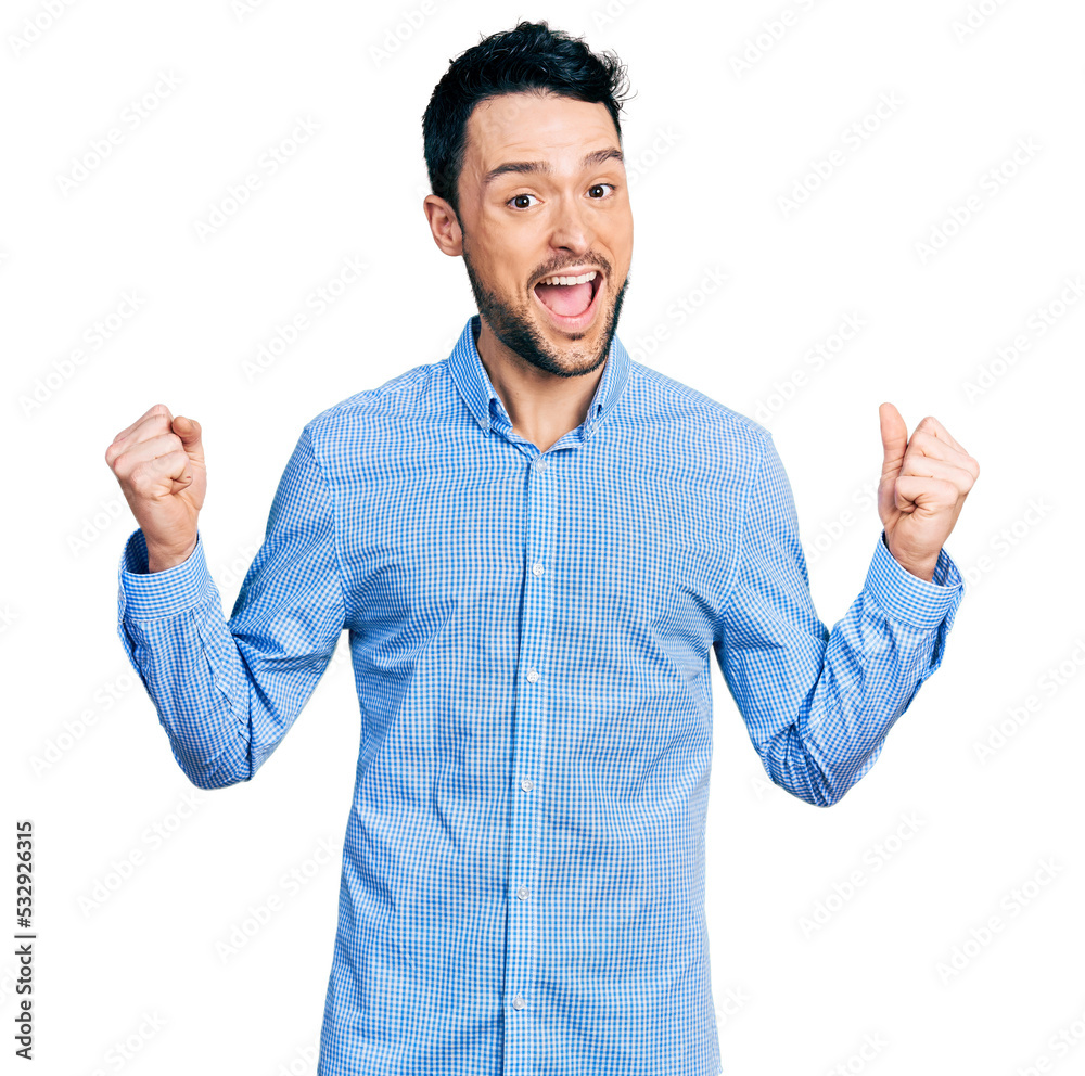 Naklejka premium Hispanic man with beard wearing casual business shirt celebrating surprised and amazed for success with arms raised and open eyes. winner concept.