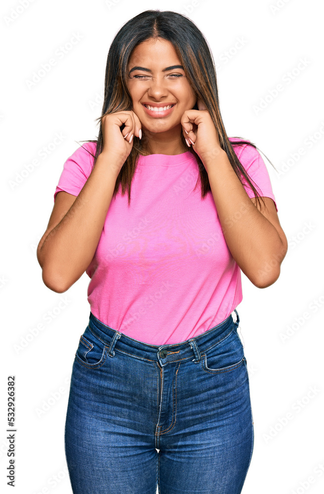 Young latin girl wearing casual clothes covering ears with fingers with annoyed expression for the noise of loud music. deaf concept. Young latin girl wearing casual clothes covering ears with fingers with annoyed expression for the noise of loud music. deaf concept.