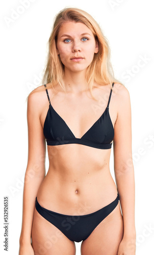 Young beautiful blonde woman wearing bikini relaxed with serious expression on face. simple and natural looking at the camera.