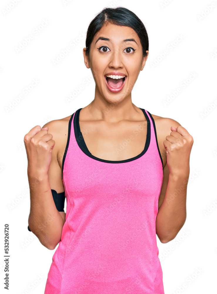 Beautiful asian young sport woman wearing sportswear and arm band celebrating surprised and amazed for success with arms raised and open eyes. winner concept. Beautiful asian young sport woman wearing sportswear and arm band celebrating surprised and amazed for success with arms raised and open eyes. winner concept.