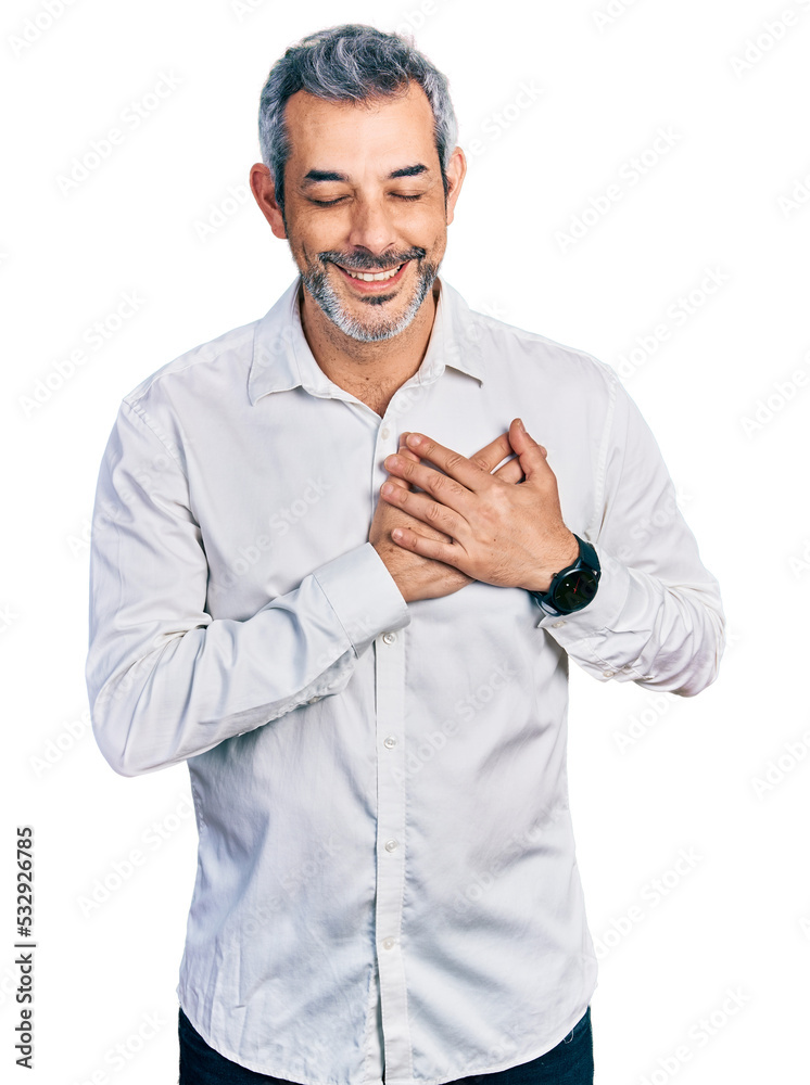 Middle age hispanic with grey hair wearing casual white shirt smiling with hands on chest with closed eyes and grateful gesture on face. health concept. Middle age hispanic with grey hair wearing casual white shirt smiling with hands on chest with closed eyes and grateful gesture on face. health concept.