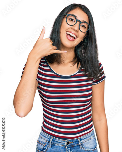 Beautiful asian young woman wearing casual clothes and glasses smiling doing phone gesture with hand and fingers like talking on the telephone. communicating concepts.