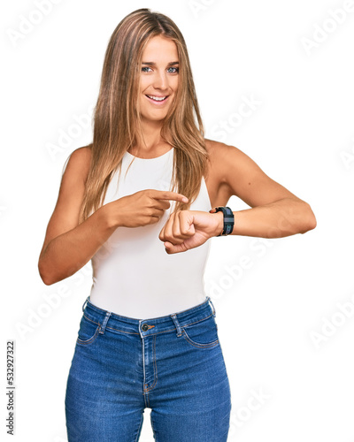 Young blonde woman wearing casual style with sleeveless shirt in hurry pointing to watch time, impatience, upset and angry for deadline delay © Krakenimages.com