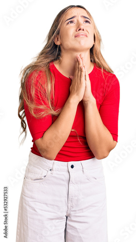 Young beautiful blonde woman wearing casual clothes begging and praying with hands together with hope expression on face very emotional and worried. begging. photo