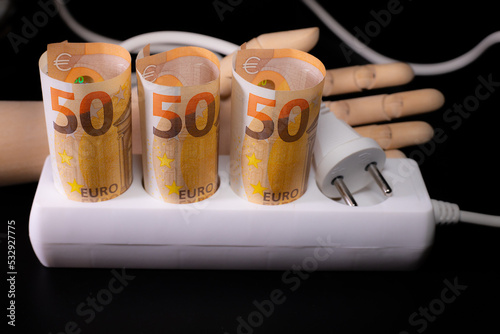 Expensive for electricity consumers. Electric plugs on euro banknotes with wooden man. Increase in energy bill prices.