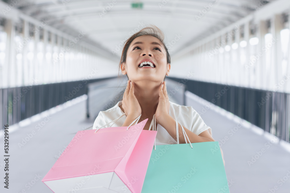 Portrait of happy smiling woman with shopping bags in corridor walk way. Beautiful woman with a paper bag. Portrait of happy smiling woman with shopping bags in corridor walk way. Beautiful woman with a paper bag.