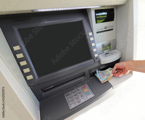 young person taking money banknotes from an ATM machine