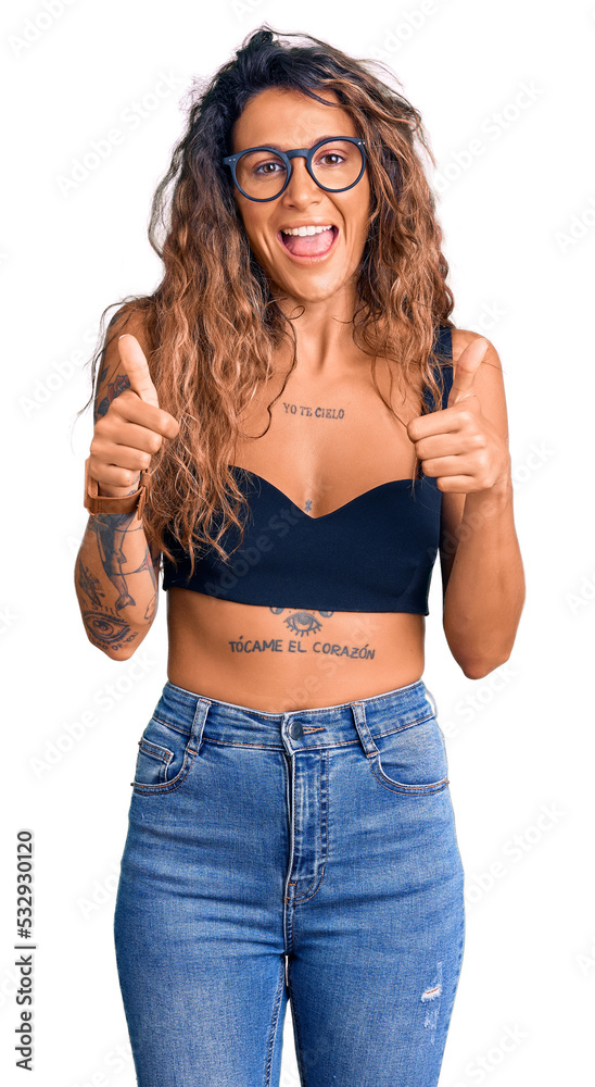 Young hispanic woman with tattoo wearing casual clothes and glasses success sign doing positive gesture with hand, thumbs up smiling and happy. cheerful expression and winner gesture. Young hispanic woman with tattoo wearing casual clothes and glasses success sign doing positive gesture with hand, thumbs up smiling and happy. cheerful expression and winner gesture.