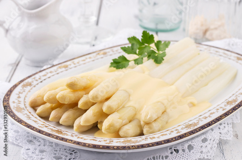 Traditional style steamed white asparagus with sauce hollandaise served as close-up on a classic design plate photo