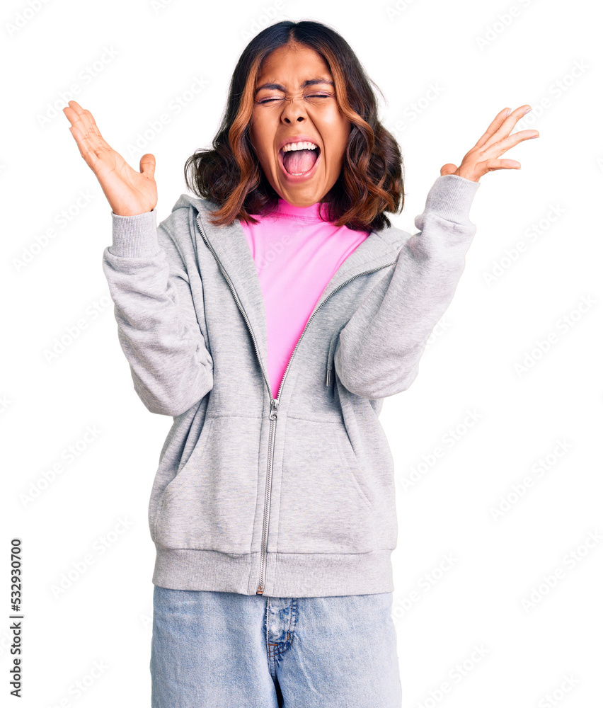 Young beautiful mixed race woman wearing casual sporty clothes celebrating mad and crazy for success with arms raised and closed eyes screaming excited. winner concept Young beautiful mixed race woman wearing casual sporty clothes celebrating mad and crazy for success with arms raised and closed eyes screaming excited. winner concept