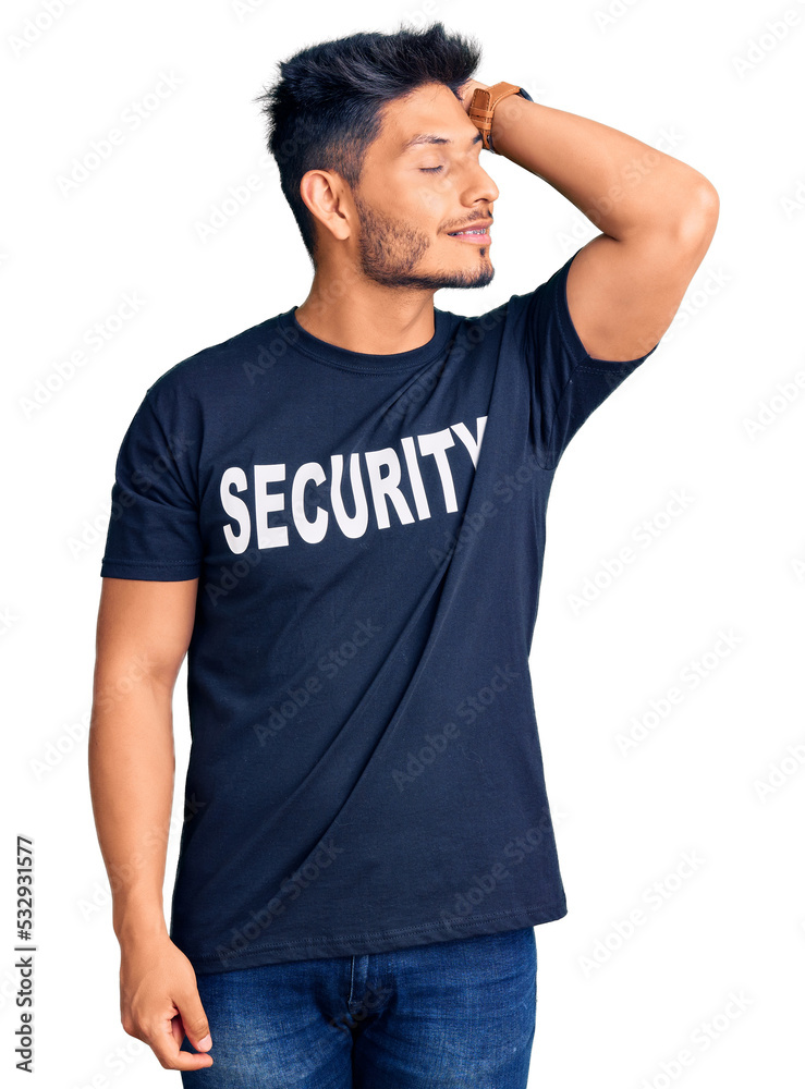 Handsome latin american young man wearing security t shirt smiling confident touching hair with hand up gesture, posing attractive and fashionable Handsome latin american young man wearing security t shirt smiling confident touching hair with hand up gesture, posing attractive and fashionable
