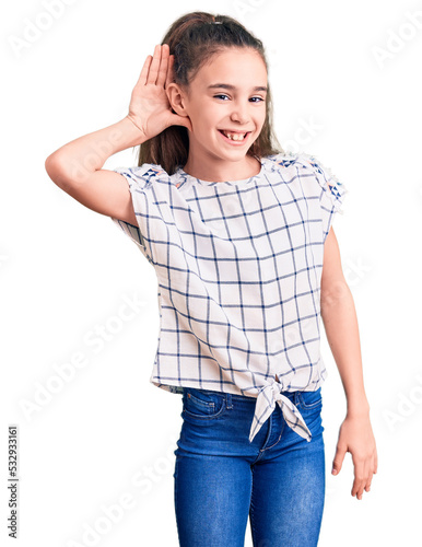Cute hispanic child girl wearing casual clothes smiling with hand over ear listening an hearing to rumor or gossip. deafness concept.