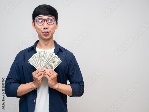 Excited asian man hold a lot of money gesture looking at copy space
