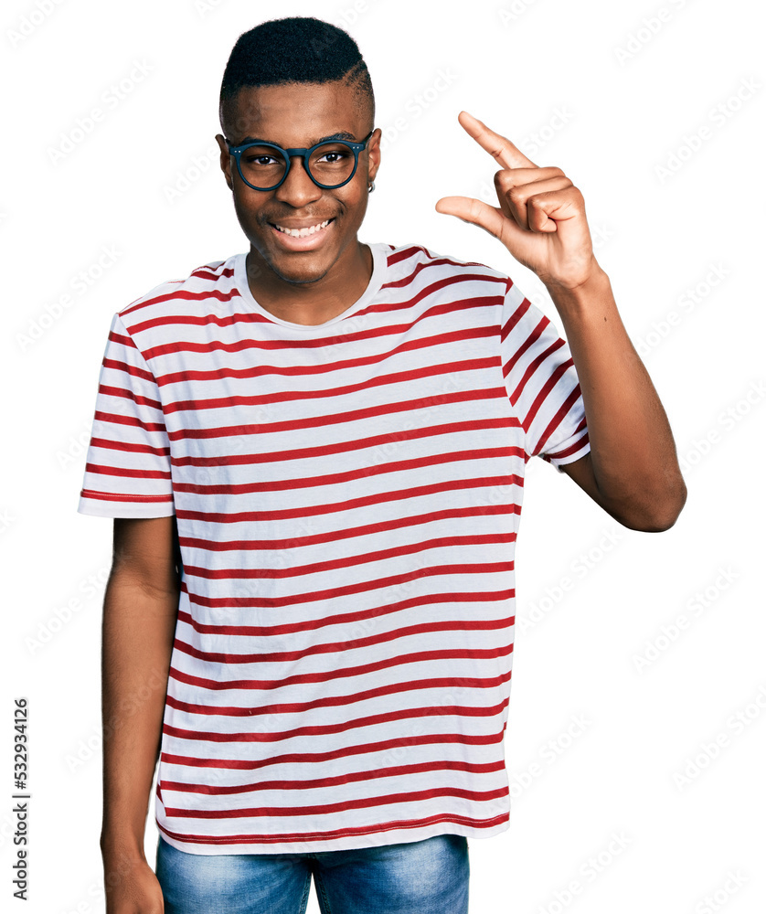 Young african american man wearing casual t shirt and glasses smiling and confident gesturing with hand doing small size sign with fingers looking and the camera. measure concept. Young african american man wearing casual t shirt and glasses smiling and confident gesturing with hand doing small size sign with fingers looking and the camera. measure concept.