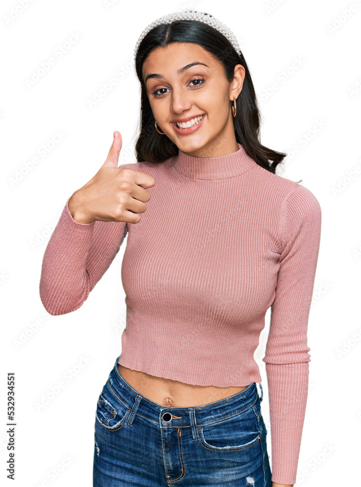 Young hispanic girl wearing casual clothes doing happy thumbs up gesture with hand. approving expression looking at the camera showing success. Young hispanic girl wearing casual clothes doing happy thumbs up gesture with hand. approving expression looking at the camera showing success.