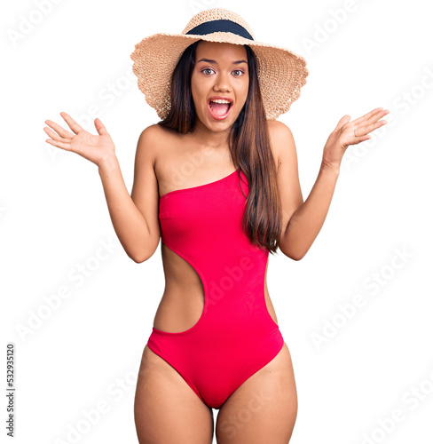 Samolepka Young beautiful latin girl wearing swimwear and summer hat celebrating crazy and amazed for success with arms raised and open eyes screaming excited