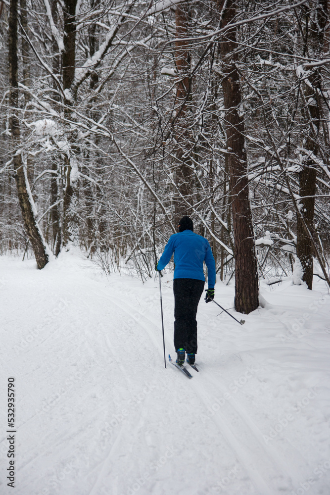 a man is skiing in the forest. Snow-covered white park