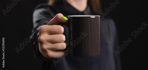 mockup of a black mug in female hands on a dark background