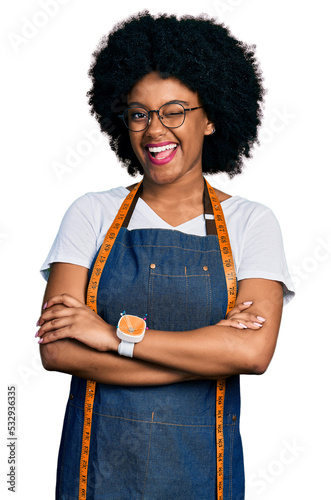 Young african american woman dressmaker designer wearing atelier apron winking looking at the camera with sexy expression, cheerful and happy face. photo