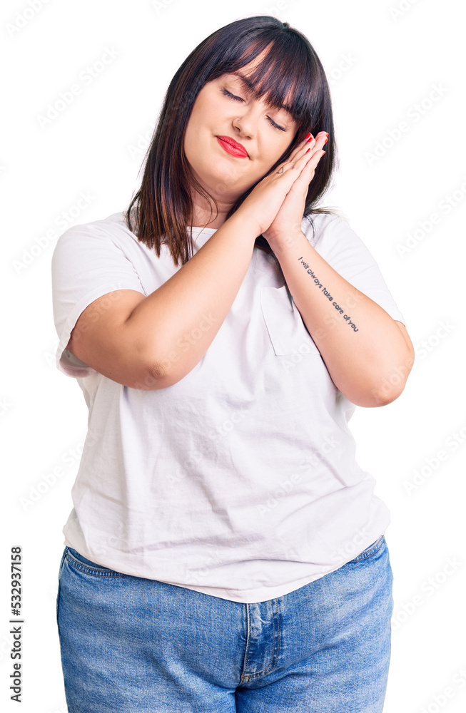 Young plus size woman wearing casual clothes sleeping tired dreaming and posing with hands together while smiling with closed eyes. Young plus size woman wearing casual clothes sleeping tired dreaming and posing with hands together while smiling with closed eyes.