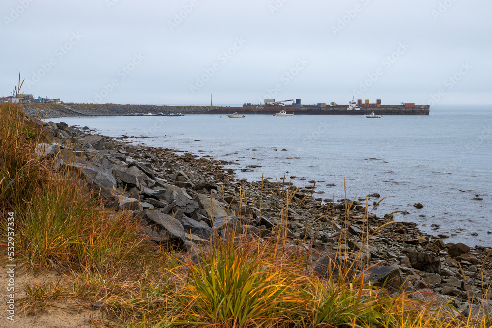 View of the pier in the sea bay. Motor boats near the pier. Autumn seascape. Overcast weather. Gertner Bay, Sea of Okhotsk, Magadan Region, Russian Far East.